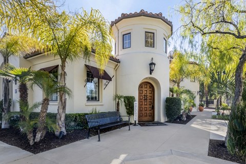 the front of a house with a wooden door and a bench